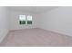 Spacious bedroom with light gray carpet and two large windows at 10813 Rolling Moss Rd, Tampa, FL 33647