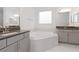 Bathroom with soaking tub, double vanity, and gray cabinets at 10813 Rolling Moss Rd, Tampa, FL 33647