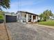 Single story home with detached garage, gravel driveway, and manicured lawn at 9913 Alavista Dr, Gibsonton, FL 33534