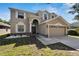 Two-story house with tan siding, large driveway, and landscaped yard at 13951 Caden Glen Dr, Hudson, FL 34669