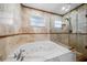 Bathroom with a large soaking tub, glass shower, and marble flooring at 5805 8Th Avenue W Dr, Bradenton, FL 34209