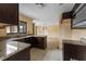 Kitchen featuring dark cabinets, granite countertops, a window, and a view to the dining room at 15635 Bear Creek Dr, Tampa, FL 33624