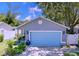 Charming single-story home features a well-kept lawn, vibrant landscaping, and a striking light-blue two-car garage door at 4477 67Th N St, St Petersburg, FL 33709