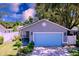 Charming single-story home features a well-kept lawn, vibrant landscaping, and a striking light-blue two-car garage door at 4477 67Th N St, St Petersburg, FL 33709