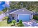 Charming single-story home features a well-kept lawn, vibrant landscaping, and a striking light-blue two-car garage door at 4477 67Th N St, St Petersburg, FL 33709
