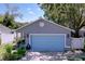 Inviting one-story home showcasing a bright blue garage door, a landscaped front yard, and mature shade trees at 4477 67Th N St, St Petersburg, FL 33709