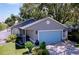 Charming single-story home featuring a well-manicured lawn, a blue garage door and mature trees at 4477 67Th N St, St Petersburg, FL 33709