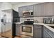 Modern kitchen with stainless steel appliances and gray cabinets at 4538 Kennewick Pl, Riverview, FL 33578