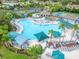 Community pool showcasing lounge chairs, shade umbrellas, palm trees, and lush landscaping at 120 Knollpoint Dr, Sun City Center, FL 33573