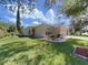 Single-story home with a red door, lush green lawn, and mature landscaping at 11201 Belle Haven Dr, New Port Richey, FL 34654