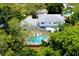 Aerial view of a house with a screened in pool surrounded by lush trees and a grey shingled roof at 31 Island Way # 907, Clearwater Beach, FL 33767