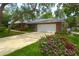 View of the well-maintained two-car garage with a long driveway and colorful flowers in the landscaped yard at 31 Island Way # 907, Clearwater Beach, FL 33767