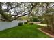 A well-manicured yard featuring a white picket fence and lush green grass with mature shady trees at 31 Island Way # 907, Clearwater Beach, FL 33767