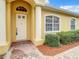 Inviting front entrance with a white door, large pillar, and colorful brick walkway complemented by lush landscaping at 4737 Casswell Dr, New Port Richey, FL 34652