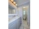 Bathroom with light gray vanity, marble countertop, decorative mirror, and tile floors at 6924 Greenhill Pl, Tampa, FL 33617