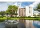 Condo building with pond, fountain, lush landscaping, and reflection at 11590 Shipwatch Dr # 548, Largo, FL 33774