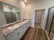 Bathroom featuring double sinks with granite countertops, wood floors, and a walk-in shower at 18208 Beach Ranch Ter, Lakewood Ranch, FL 34211