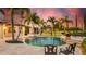 Backyard view of a luxury swimming pool with lush palm trees and stone accents at sunset at 10603 Low Oak Ter, Thonotosassa, FL 33592