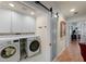 Well-organized laundry room with modern appliances, white cabinets, and a sliding barn door at 1661 Watermark Ne Cir, St Petersburg, FL 33702