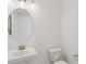 Powder room with white pedestal sink, oval mirror, decorative lighting and a low-flow toilet at 31907 Anchor Point Dr, Wesley Chapel, FL 33545