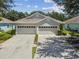 Two-car garage, light gray vinyl siding, and well-manicured lawn at 6919 Surrey Hill Pl, Apollo Beach, FL 33572