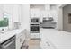 Bright kitchen with white cabinets, stainless appliances, herringbone backsplash, apron sink, and hardwood floors at 2510 W Cleveland St # 2, Tampa, FL 33609