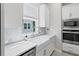Bright kitchen features white cabinets, stainless steel appliances, herringbone backsplash, apron sink, and hardwood floors at 2510 W Cleveland St # 2, Tampa, FL 33609