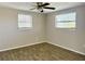 Bedroom features light-colored walls, wood-look floors, ceiling fan, and natural light from windows at 3245 Bigelow Dr Dr, Holiday, FL 34691
