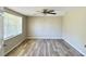 Bright bedroom featuring wood-look floors, ceiling fan, and large window at 3245 Bigelow Dr Dr, Holiday, FL 34691