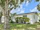 Side view of a single story home with mature landscaping and a large tree at 3245 Bigelow Dr Dr, Holiday, FL 34691