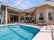 Relaxing pool area with screened enclosure, patio furniture, and lush landscaping at 13217 Thoroughbred Dr, Dade City, FL 33525