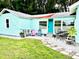 Cute bungalow with teal exterior, patio seating, and landscaped yard at 1478 Alternate Keene Rd, Largo, FL 33771