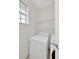 Bright laundry room featuring a white front-loading washer and dryer, along with wire shelving for storage at 6419 Marbella Blvd, Apollo Beach, FL 33572
