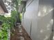 Side yard with a narrow pathway and mature foliage at 120 S San Remo Ave, Clearwater, FL 33755