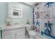 Bathroom with white vanity, seashell shower curtain, and decorative mirror at 4950 Gulf Blvd # 104, St Pete Beach, FL 33706