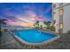 Evening view of condo pool area with lighting and palm trees at 4950 Gulf Blvd # 104, St Pete Beach, FL 33706