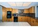 Modern kitchen with wood cabinets, granite counters, and black appliances at 7037 Sunset S Dr # 602, South Pasadena, FL 33707