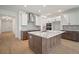 Well-lit kitchen featuring a large island, stainless steel appliances, and views of the hallway and front door at 11963 Richmond Trl, Parrish, FL 34219