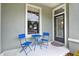 Inviting front porch with black front door, window, and bistro seating set at 10022 Bentley Way, Tampa, FL 33626