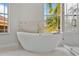 Spa-like bathroom featuring a freestanding tub next to bright windows and a modern glass shower enclosure at 1233 Acappella Ln, Apollo Beach, FL 33572