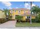 A vibrant yellow two-story home with lush landscaping, a charming facade, and ample curb appeal at 1233 Acappella Ln, Apollo Beach, FL 33572