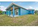 Exterior shot showing a backyard with a bright blue home and covered patio at 272 Diogenes St, Dunedin, FL 34698