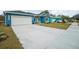 Charming blue single-Gathering home with a wide driveway and a two-car garage, complemented by a neatly manicured lawn at 272 Diogenes St, Dunedin, FL 34698