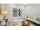 Bright living room with neutral-toned furniture, wood-look tile floors, and sliding glass doors to the outdoor area at 272 Diogenes St, Dunedin, FL 34698