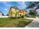 Two-story house with a yellow exterior, palm trees, and a well-maintained lawn at 10820 Carloway Hills Drive, Wimauma, FL 33598