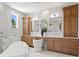 Luxurious bathroom featuring a soaking tub, wooden cabinetry, double sinks, and elegant mirrors at 4536 W Swann Ave, Tampa, FL 33629
