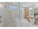 Bright bathroom with glass-enclosed shower, soaking tub, wooden vanity, and natural light from windows at 4536 W Swann Ave, Tampa, FL 33629