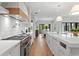 Bright kitchen featuring white cabinetry, stainless steel appliances, and a large island with a sink and wood floors at 4536 W Swann Ave, Tampa, FL 33629