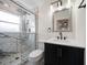 Updated bathroom with a glass shower enclosure and marble tile, dark vanity and lighting above the mirror at 6750 W Flamingo S Way, St Petersburg, FL 33707