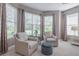 Bedroom sitting area with two chairs and ottoman, large windows and natural light at 5014 Ruby Flats Dr, Wimauma, FL 33598